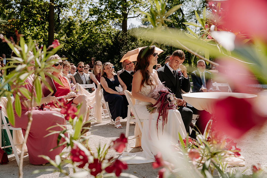 para młoda i goście na plenerowym ślubie z różowymi kwiatami