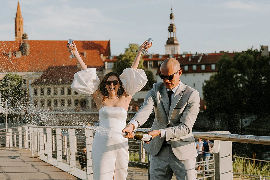 para młoda otwiera szampana na tle ostrowa tumskiego